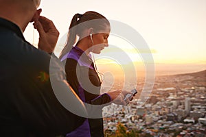 Couple, fitness and music with phone in sunset for podcast, radio player or sound on mountain. Man and woman listening