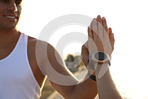 Couple with fitness trackers giving each other high fives after training outdoors, closeup