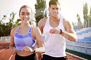 Couple with fitness trackers running at stadium