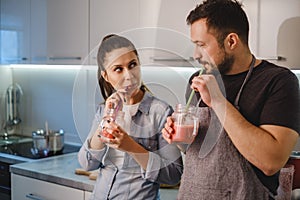 Couple flirting in the kitchen while drinking smoothie