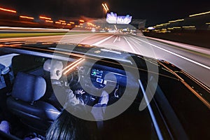 Couple of friends in a luxury car driving at night