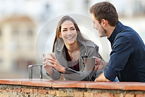 Couple or friends talking in a terrace drinking coffee