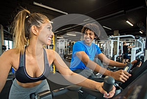 Couple of friends working out at the gym on a bike