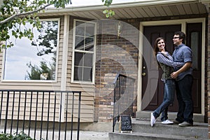 Couple in front of new home holding sold blackboard sign photo