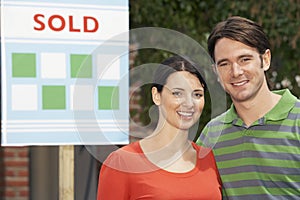 Couple In Front Of New Home With Sold Sign