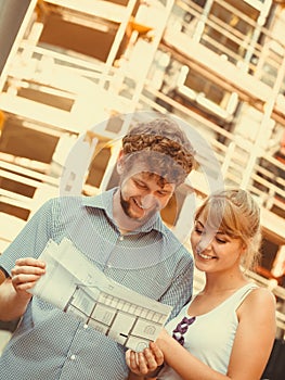 Couple on front of new house with blueprint project