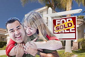 Couple in Front of Sold Real Estate Sign and House