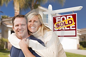 Couple in Front of Sold Real Estate Sign and House