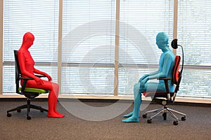 Couple in full body elastic suits sitting on armchairs in sunny space