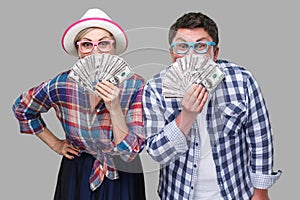 Couple of funny friends, adult man and woman in casual checkered shirt standing together holding, covering mouth with fan of