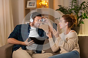 Couple with gadgets listening to music at home