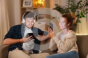 Couple with gadgets listening to music at home