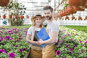 Couple of gardeners holding clipboards by flowers photo