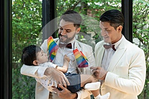 Couple gay carrying adopted child together in wedding day