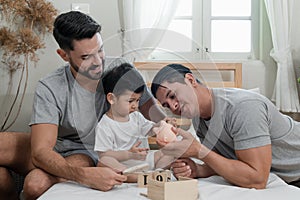 A couple gay parent playing with adopted child in bedroom photo