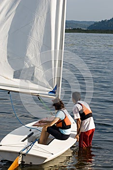 Couple Getting into Sailboat on Water - Vertical photo