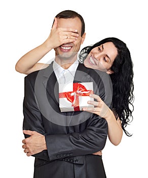 Couple with gift box, studio portrait on white. Woman close man eyes. Dressed in black suit.