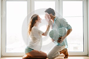 Couple girl and guy play with pillows near window.