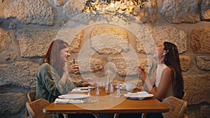 Couple girls mates laughing in cafeteria drinking beverages under lamp light.