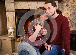 Couple with glass of champagne together near fireplace