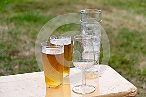 Couple of glasses of beer sitting on top of wooden table