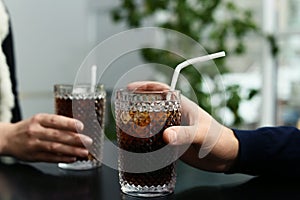 Couple with glasses of cold cola at table in cafe