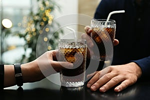 Couple with glasses of cold cola at table in cafe