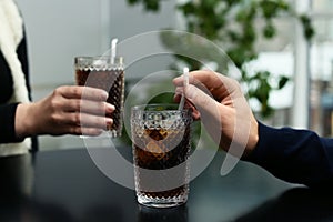 Couple with glasses of cold cola at table in cafe