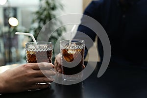 Couple with glasses of cold cola at table in cafe