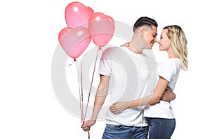 couple going to kiss boyfriend holding bundle of heart shaped balloons