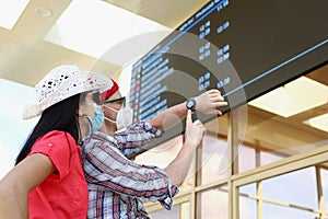 Couple going on trip during pandemic, flight delay, man point on wristwatch.