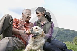 Couple With Golden Retriever On Grass