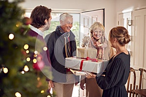 Couple Greeting Senior Parents As They Arrive With Presents To Celebrate Christmas