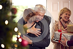 Couple Greeting Senior Parents As They Arrive With Presents To Celebrate Christmas