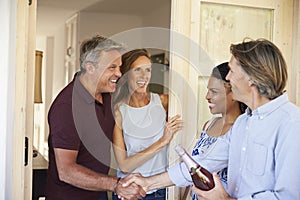 Couple greeting their guests at the door of their home photo