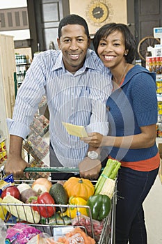 Couple With Grocery Shopping In Supermarket Aisle