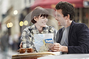 Couple With Guidebook At Outdoor Cafe