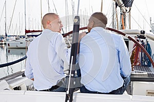 A couple of guys in blue shirts chatting on private yacht in the port