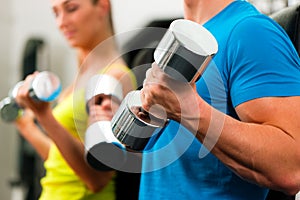 Couple in gym exercising with dumbbells