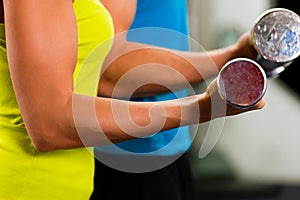 Couple in gym exercising with dumbbells