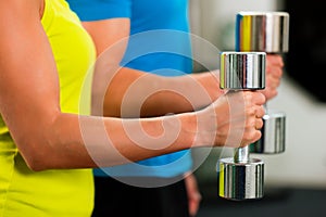 Couple in gym exercising with dumbbells