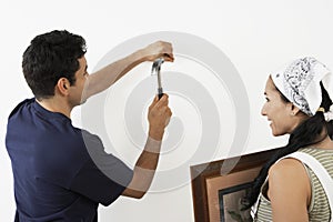 Couple Hammering Nail Into Wall