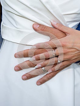 Couple hand wedding rings on bride and groom fingers hands on marriage white dress background