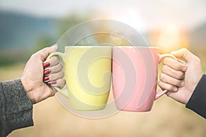 Couple hands clink hot coffee mug outdoor in the morning photo