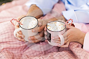 Couple hands with cup of hot chocolate close up image