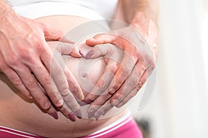 Couple with hands in a heart shape on pregnant belly