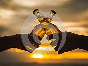 Couple hands holding beer bottles and clanging on the sunset beach. Party, Holiday, Summer, Friendship Concept.