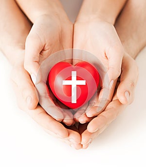 Couple hands holding heart with cross symbol