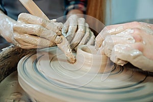 Couple hands sculpting clay pot at the pottery`s wheel. Date at the pottery workshop. Closeup picture