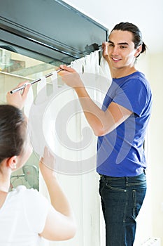 Couple hanging curtains at window